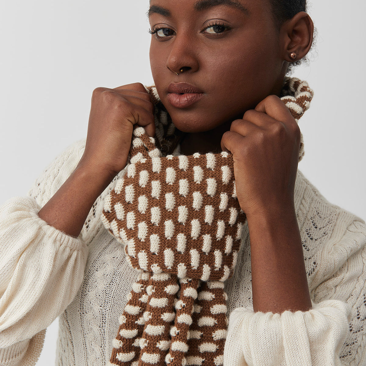 model wearing a brown and beige patterned baby alpaca scarf.