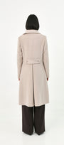 A model viewed from the back wearing a long, light beige baby alpaca coat with a martingale.