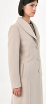 A model wearing a beige baby alpaca coat with buttons front and side pockets.