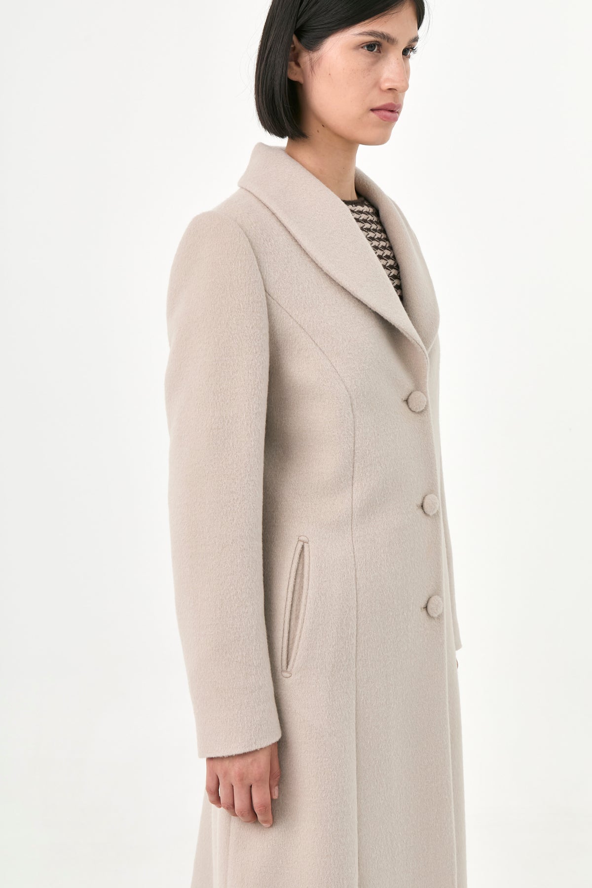 A model wearing a beige baby alpaca coat with buttons front and side pockets.