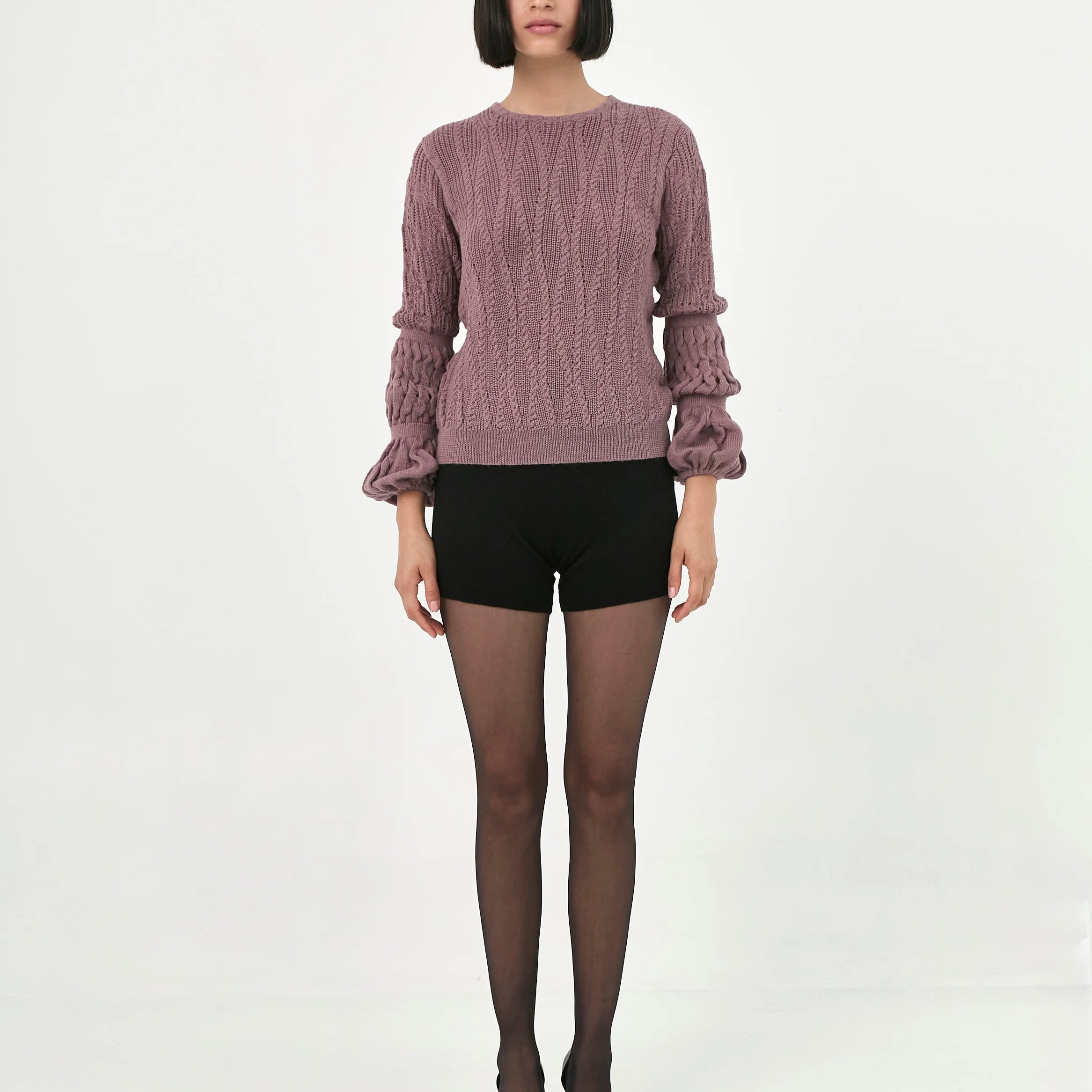 A model wearing a dusty rosebaby alpaca knit sweater with ruffled long sleeves.