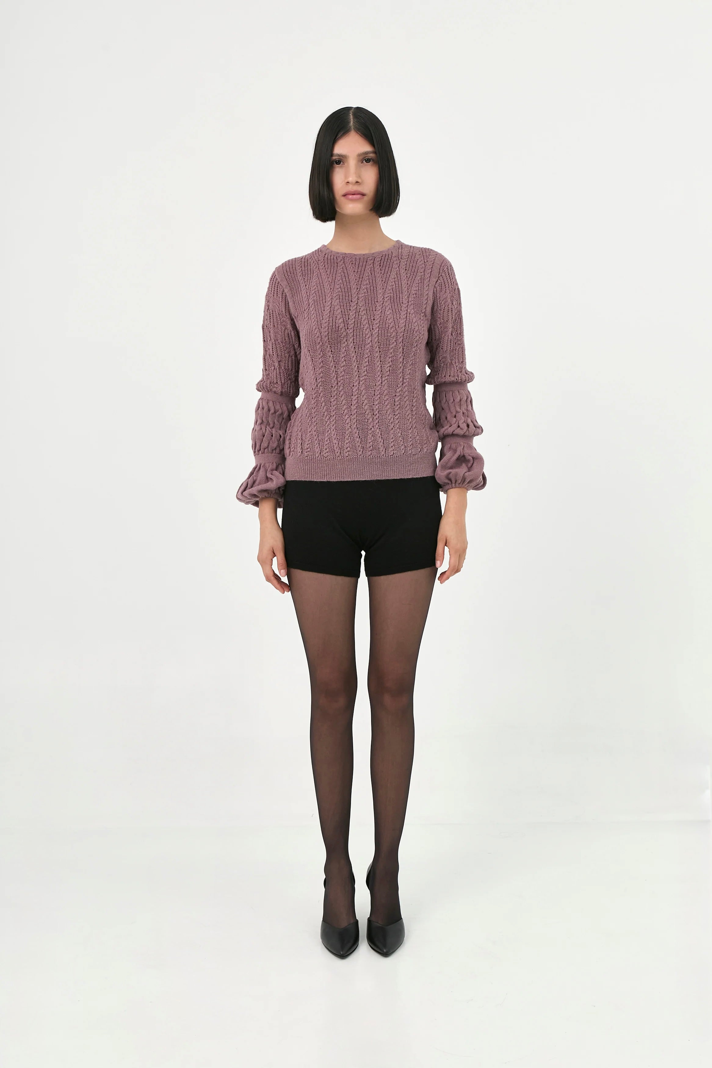 A model wearing a dusty rosebaby alpaca knit sweater with ruffled long sleeves.