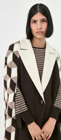 A model wearing a dark brown open-front cape coat with a thick cream collar and geometric patterned sleeves.